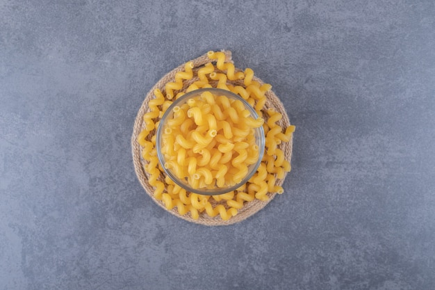 Raw dry macaroni in glass bowl.