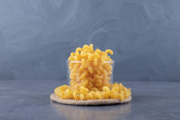 Raw dry macaroni in glass bowl.