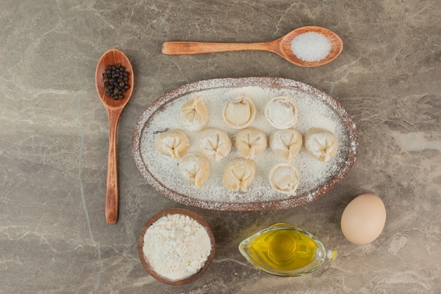 Free photo raw dumplings with egg, oil, flour and spoons .