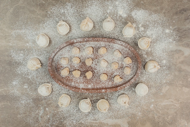 Free photo raw dumplings on wooden board with flour .