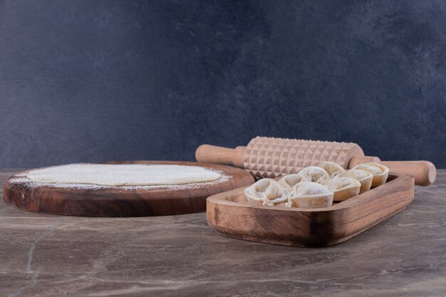 Raw dumplings on wooden board .