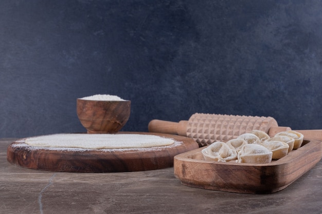 Raw dumplings on wooden board.