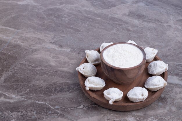 Raw dumplings on wooden board.