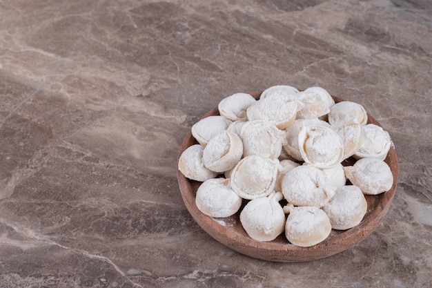 Raw dumplings on wooden board .