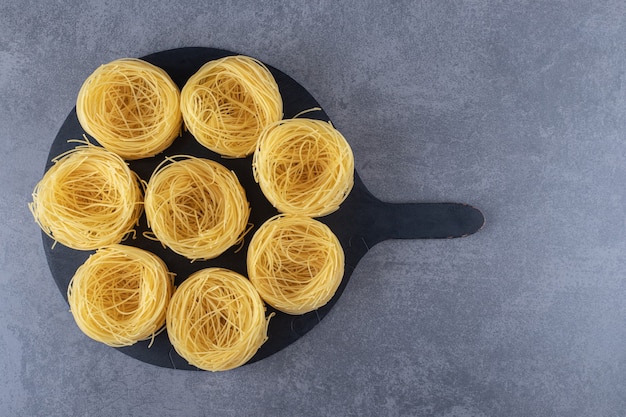 Raw egg noodles on black board.