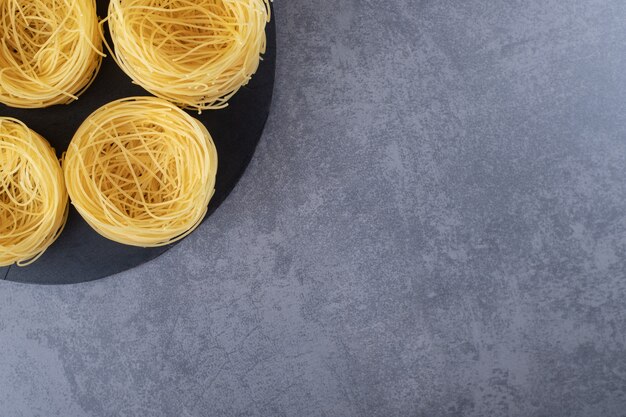 Raw egg noodles on black board.