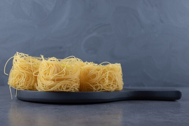 Raw egg noodles on black board.