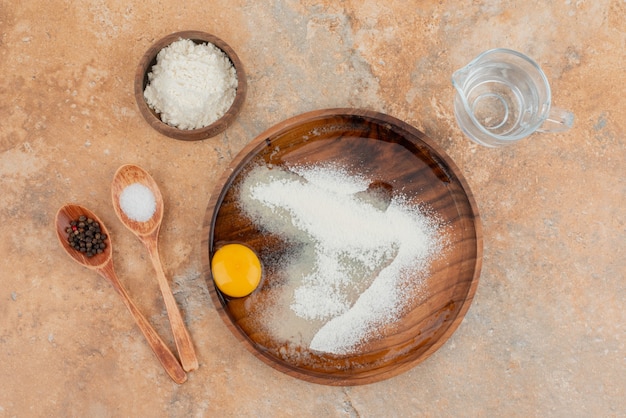 Free photo raw egg with spoons and wooden board .