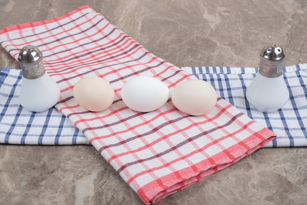 Raw eggs and spices with tablecloth on marble surface. High quality photo