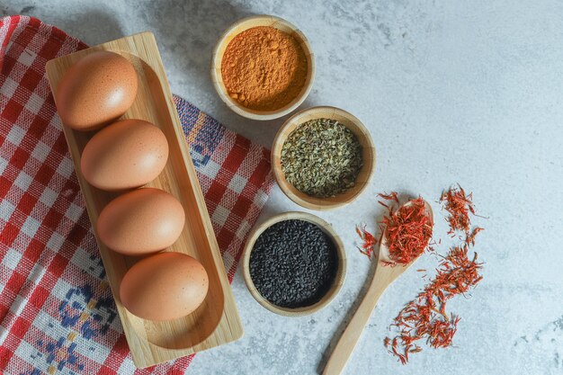 Raw eggs and various spices on stone background.