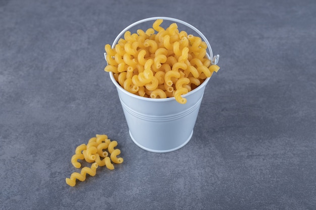 Free photo raw elbow macaroni in metal bucket.