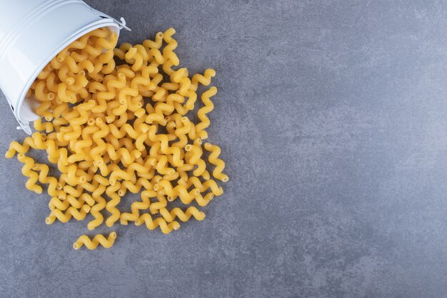 Raw elbow macaroni out of metal bucket. 