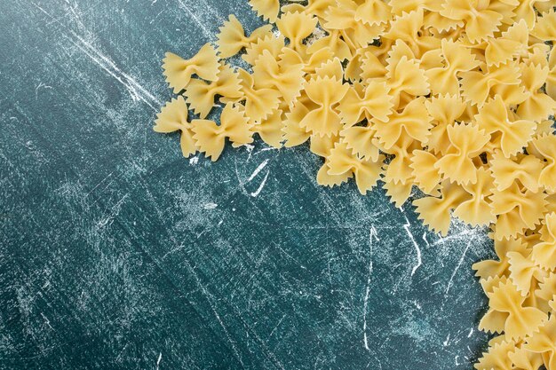 Raw farfalle pasta on blue space. 