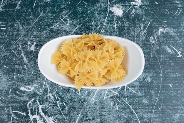 Free photo raw farfalle pasta on white plate.