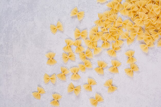 Raw farfalle pasta on white surface