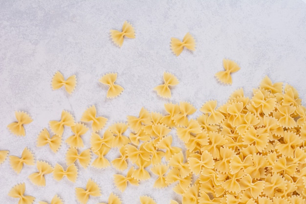 Raw farfalle pasta on white surface