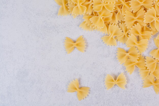 Raw farfalle pasta on white surface
