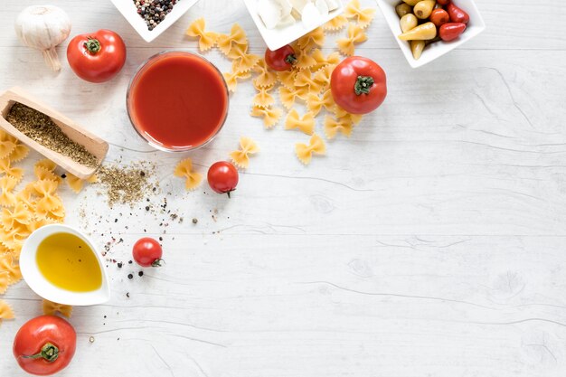 Raw farfalle pasta with it's ingredient on white wooden backdrop