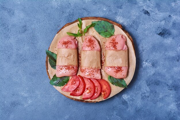 Raw fillet with spices and herbs on a wooden board on blue