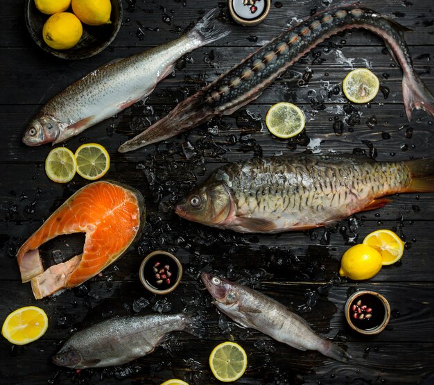 生の魚は、レモンスライスの周りの黒い木製のテーブルに並べ替えます。