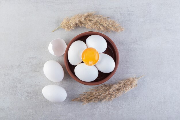 Raw fresh chicken eggs placed on a stone surface. 