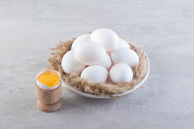 Raw fresh chicken eggs placed on a stone surface. 