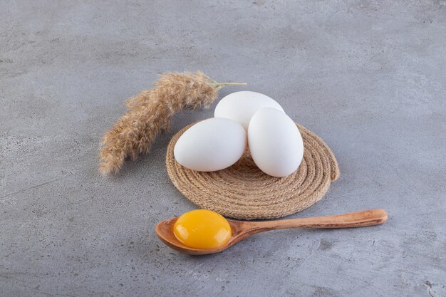 Raw fresh chicken eggs placed on a stone surface. 