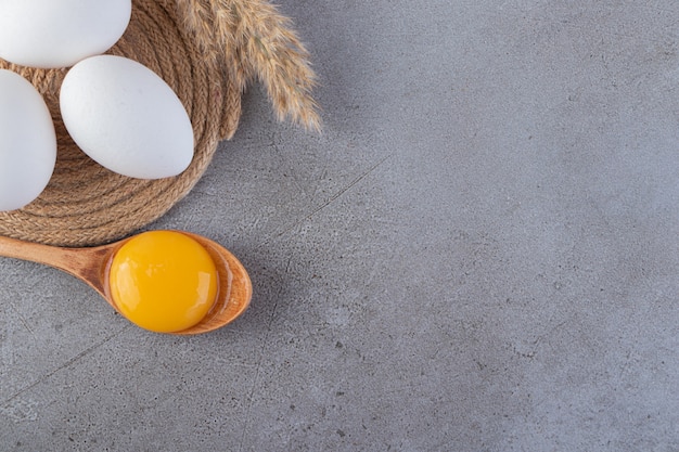 Raw fresh white chicken eggs placed on a stone background.