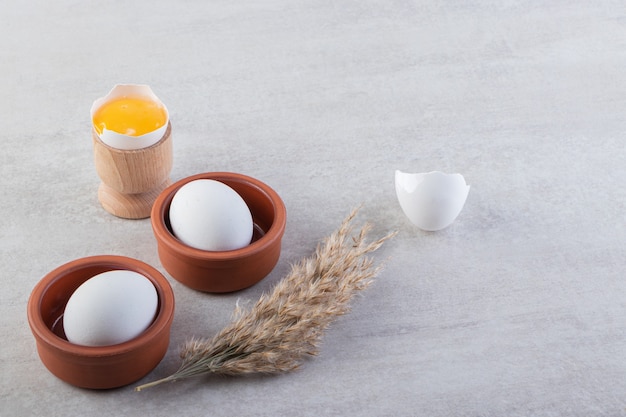 Free photo raw fresh white chicken eggs placed on a stone surface.