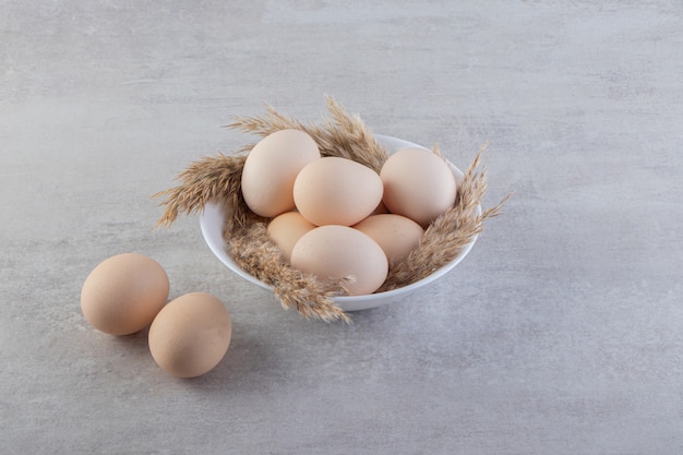 Free photo raw fresh white chicken eggs placed on a stone surface.