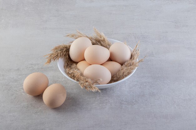 Raw fresh white chicken eggs placed on a stone surface. 