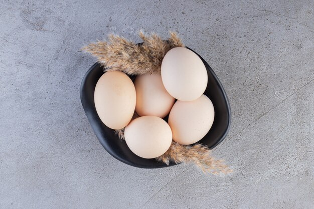 Free photo raw fresh white chicken eggs placed on a stone surface.