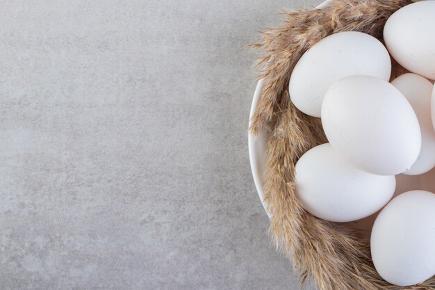 Raw fresh white chicken eggs placed on a stone surface. 