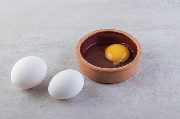 Raw fresh white chicken eggs placed on a stone surface. 