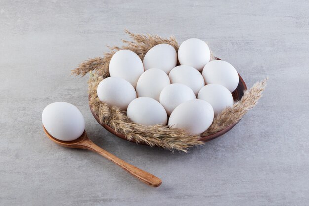 Raw fresh white chicken eggs placed on a stone surface. 