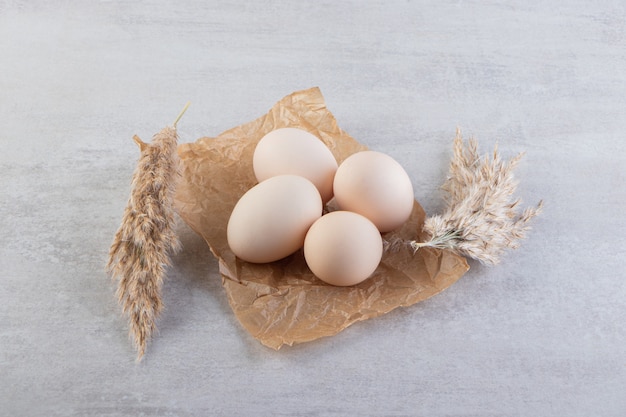 Raw fresh white chicken eggs placed on a stone surface. 