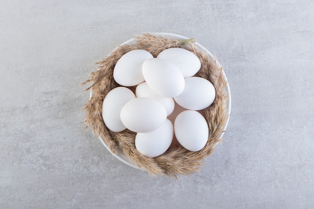 Raw fresh white chicken eggs placed on a stone surface. 