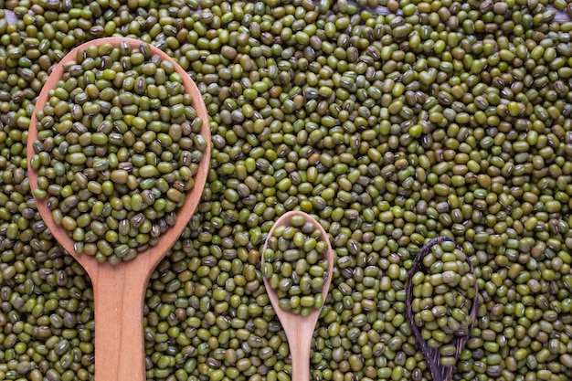 Raw green beans in a cup placed on a wooden floor.