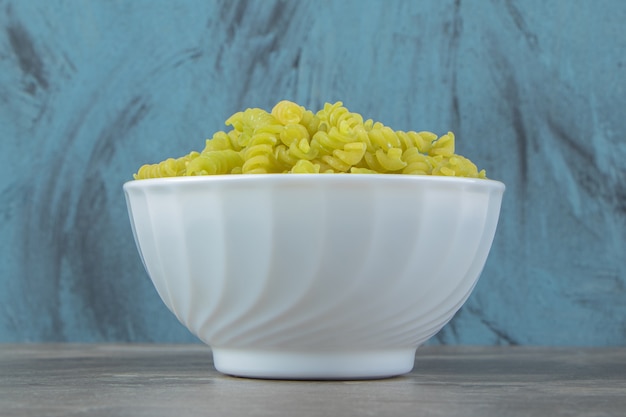 Free photo raw green fusilli in white bowl