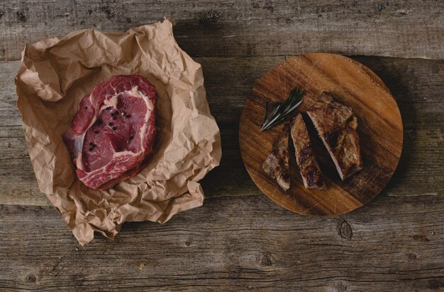 Raw and grilled steak on table