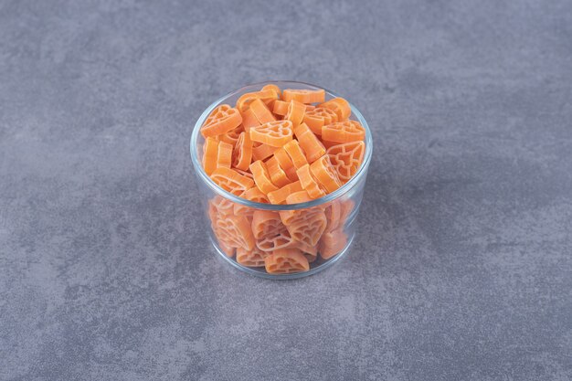 Raw heart-shaped pasta in glass bowl.