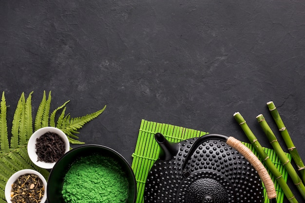 Raw herbal tea ingredient with teapot on black background