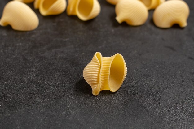 сырые итальянские макароны желтого цвета немного сформированные на темном