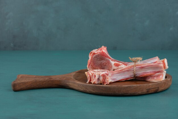 Raw lamb chops on wooden board.