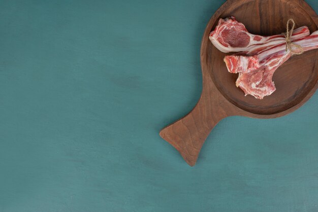 Raw lamb chops on wooden board.