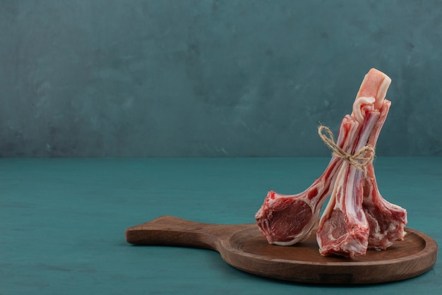 Raw lamb chops on wooden board.