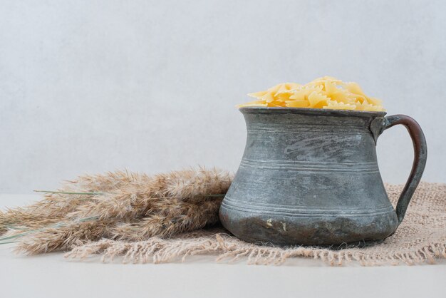 Raw macaroni in ancient kettle on burlap