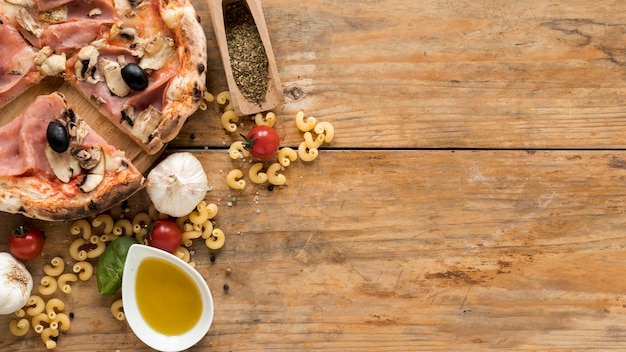 Raw macaroni past; baked pizza and fresh ingredients on wooden plank