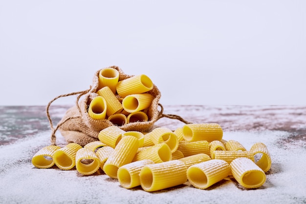 Raw macaroni on white surface. 