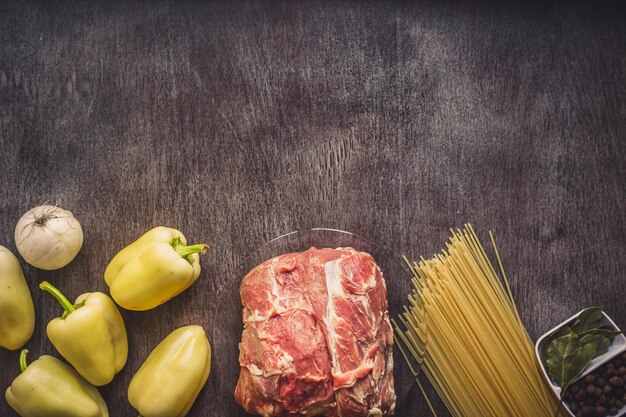 スパゲッティ、新鮮な有機野菜、タマネギ、ニンニク、スパイス、ペッパーコーン、ローズマリー、塩、パスタを調理するためのディルを添えた生肉牛肉。上面図。
